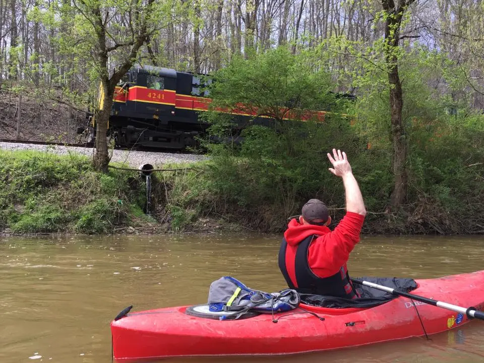 A kayaker waves to a passing Cuyahoga Valley Scenic Railroad train